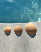 Cache tétons en silicone sans adhésifs, invisibles, disposition en bordure de piscine pour mise en scène estivale.