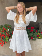 robe bohème dos nu en dentelle blanche courte avec manches évasées et chapeau de paille, modèle en plein air