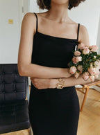 femme portant une robe noire dos nu, tenant un bouquet de fleurs roses, posant dans un salon élégant