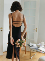 femme en robe longue noire dos nu calissa tenant un bouquet de fleurs roses dans une pièce lumineuse