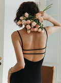 robe noire dos nu calissa avec fines bretelles, femme tenant un bouquet de roses saumonées, élégante et sophistiquée