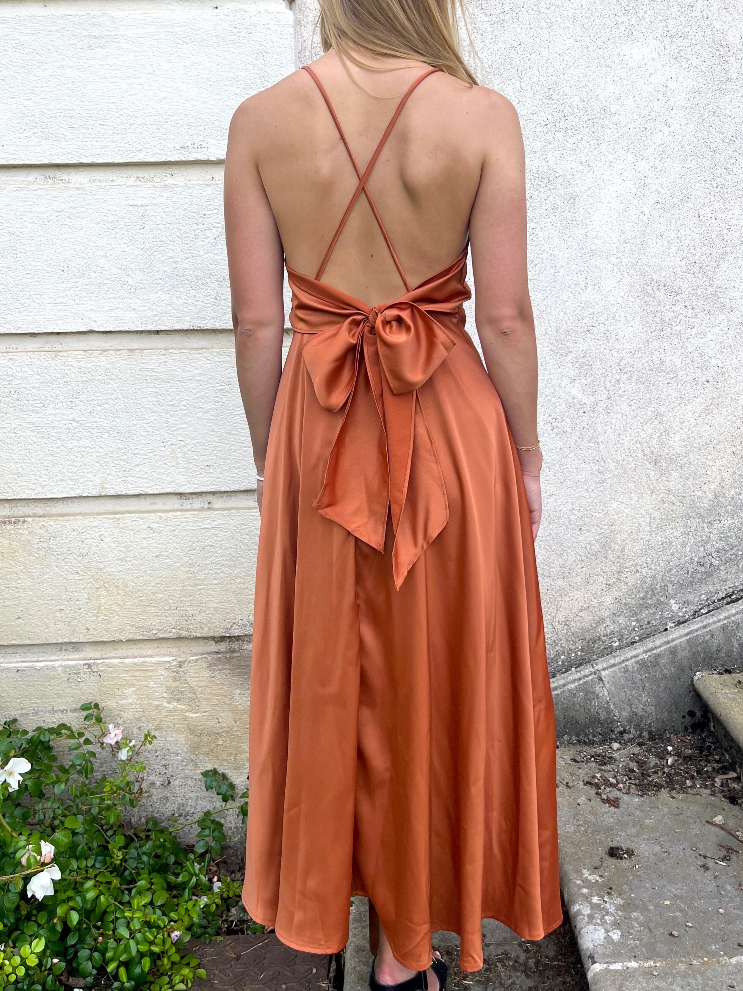 Robe en satin mi-longue couleur terre cuite avec dos nu et bretelles croisées, style élégant et chic parfaite pour l'été.